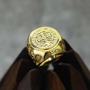 Macro-opname van de gouden Sint-Benedictusring met gedetailleerde gravure op hout