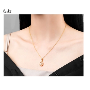 Detail showing a golden water drop pendant with sparkling crystals on a black garment