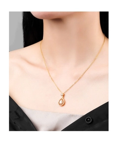 Detail of a gold-plated teardrop pendant necklace with clear crystals on a model