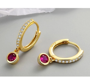 Détail macro de boucles d'oreilles S925 en argent avec zircons et pierres rouges rondes