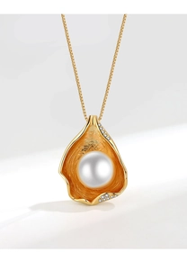 Detailed shot of a gold shell pendant with white pearl and sparkling crystals on fine chain