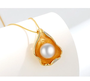 Detailed close-up of golden petal pendant with hammered texture and white pearl