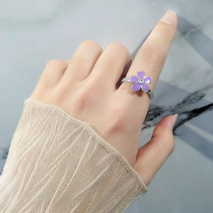 Elegant purple enamel flower ring with zircon center on female finger, silver finish