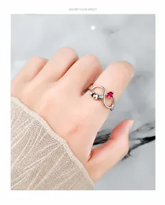 Detail of silver spinner ring with heart-shaped red zircon and infinity symbol design