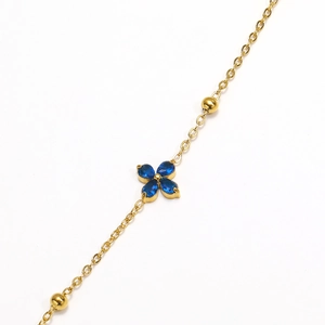 Detailed macro view of gold-plated clover bracelet with blue drop-shaped rhinestones
