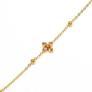 Detailed macro view of gold-plated clover bracelet with sparkling champagne gemstone inlay