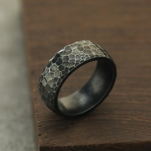 Makrodetail eines dunkelgrauen Titanstahlrings mit gehämmertem Wabenmuster-Finish