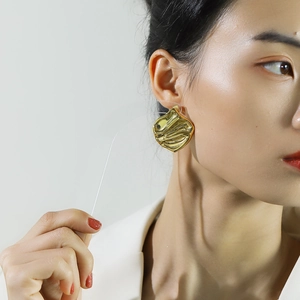 Detalle de pendientes geométricos dorados grandes llevados por una modelo de moda asiática