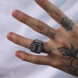 Detail eines Hip-Hop-Rings in Schwarz mit Strasssteinen auf einem männlichen Finger