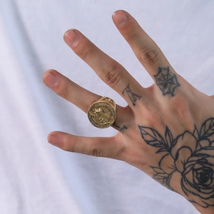 Détail d'une bague médaille Saint-Benoît dorée avec relief religieux sur fond texturé