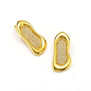 Detalle macro de pendientes geométricos de oro y titanio con pavé de cristales