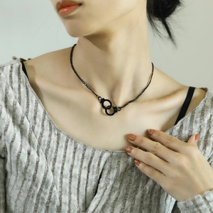 Close-up of a trendy black handcuff pendant necklace on a model's neck for a punk look