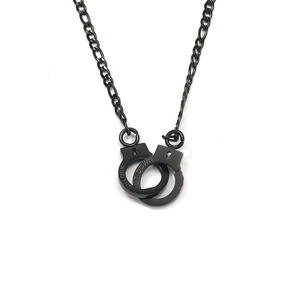 Close-up of black handcuff pendant with UNLOCK engraving on Figaro chain necklace