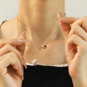 Infinity 18k gold plated titanium necklace with red zircon worn by a model