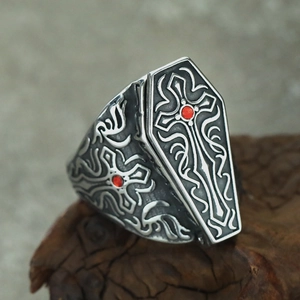 Macro view of gothic coffin ring with cross engraving and red gemstone on dark wood