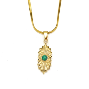 Detail van 18K gouden slangenschakelketting met zonnestraal-hanger en groene malachiet