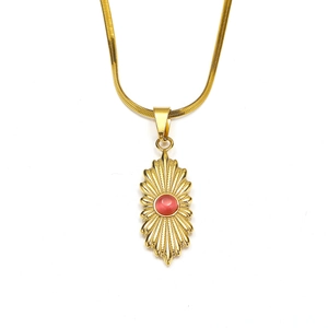 Detail van de 18K goudstalen zonnestraal hanger met rode edelsteen aan een slangenketting
