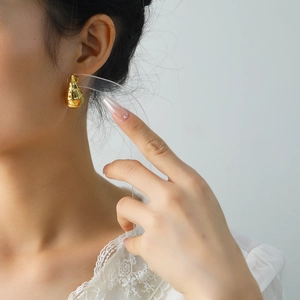 Gros plan de boucles d'oreilles spirales géométriques dorées en acier titane