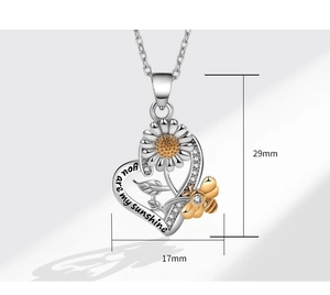 Dettaglio macro della collana a cuore con girasole, ape e incisione You are my sunshine