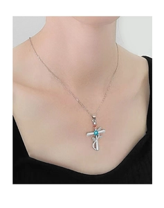 Dettaglio della collana a croce d'argento con fiore in oro rosa e gemma blu su modella