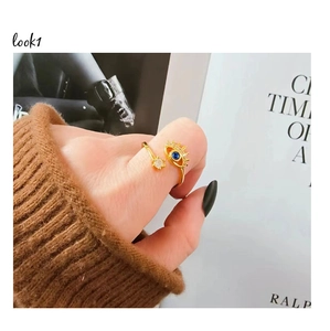 Close-up of golden Evil Eye ring with blue gem and white zircon on a model finger