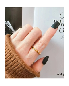 Nahaufnahme des goldenen Evil-Eye-Rings mit blauen Zirkonia am braunen Strickärmel