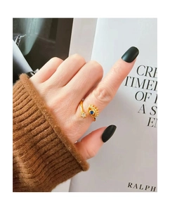Close-up of golden evil eye ring featuring a blue crystal and adjustable open band