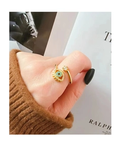 Primer plano de un anillo ojo de la suerte chapado en oro con gema azul y circón en mano