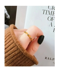 Detail eines goldenen Evil-Eye-Rings mit blauen Zirkonia, getragen auf einem Strickpullover