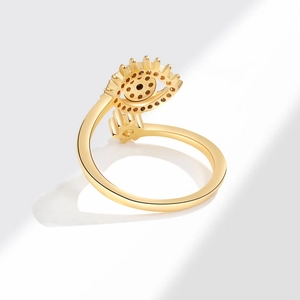 Elegante anillo envuelto en oro con motivo de ojo turco y circonitas azules en fondo blanco