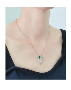 Dettaglio di una collana con ciondolo a cuore con gemma verde e incisione MOM indossata