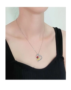 Dettaglio del ciondolo a cuore d'argento con coccinella e fiori su una modella