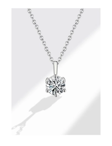 Détail macro d'un diamant rond serti dans un pendentif à six griffes en argent fini