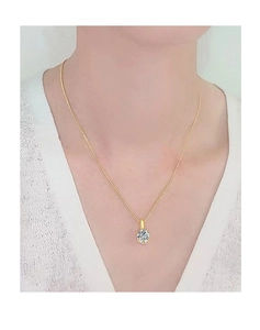 Gros plan d'un élégant collier en or 18 carats avec pendentif moissanite brillant sur le cou