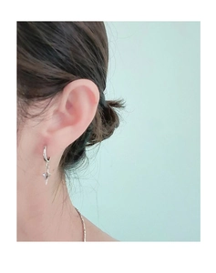 Gros plan d'une boucle d'oreille étoile en argent portée par un modèle pour un style tendance