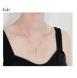 Close-up of a pear-cut yellow diamond pendant on a silver necklace worn by a model