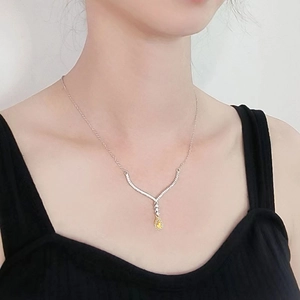 Elegant silver necklace with pear-cut yellow gemstone and white diamond halo on model