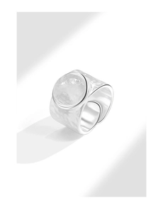 Macro shot of irregular textured silver ring with centered round white gemstone inlay