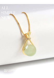Macro detail of faux nephrite jade pendant with gold ribbon knot and sparkling mini diamonds