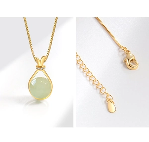 Detail of gold lucky bag pendant with faux nephrite jade and square box chain clasp