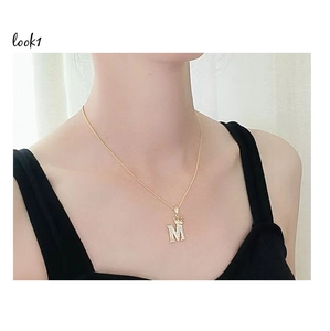 Dettaglio collana oro 18K con ciondolo lettera M a corona e zirconi brillanti incastonati