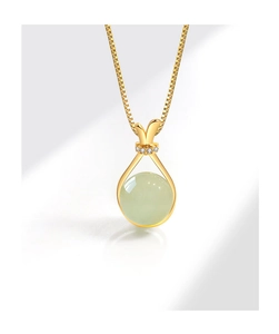 Detail shot of a lucky bag necklace with pale green Hetian jade and gold finish.