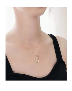 Primo piano della collana corona dorata con ciondolo lettera R e zirconi incastonati