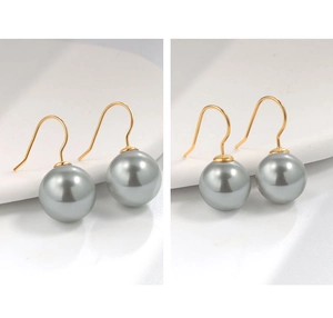 Dettaglio di perle grigie e ganci dorati su un piatto di ceramica minimalista