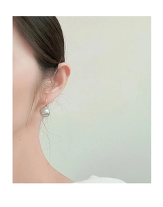 Dettaglio di orecchini con perle grigie su modella con ganci dorati e argento sterling