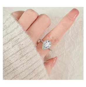 Ring mit Tropfenschliff und Halo-Design an der Hand getragen mit weißem Pullover