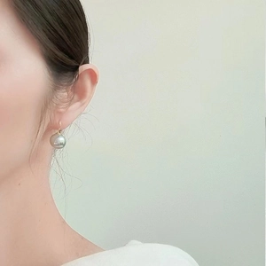 Eleganti orecchini a goccia con perle grigie e ganci dorati indossati da una modella
