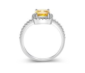 Macro view of cushion cut yellow gemstone ring with white diamond halo on silver band