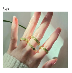 Detail of four golden rings with textured hammered finish worn on fingers as a set