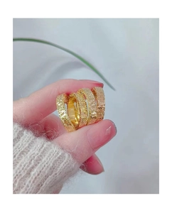 Macro detail of five gold hammered texture stackable rings held in hand
